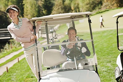 couple driving golf cart on golf course