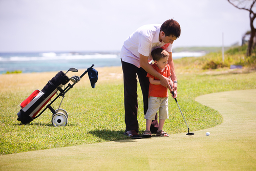 father teaching his son to play golf