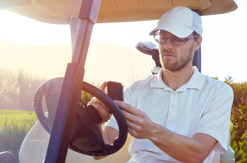Man using phone in golf cart